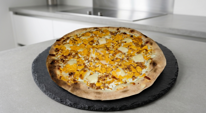 Pizza garnie de fromage cheddar, sur une pierre, avec une pâte dorée et croustillante.