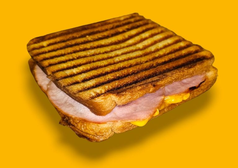 Croque monsieur toasté avec jambon et fromage sur un fond jaune.