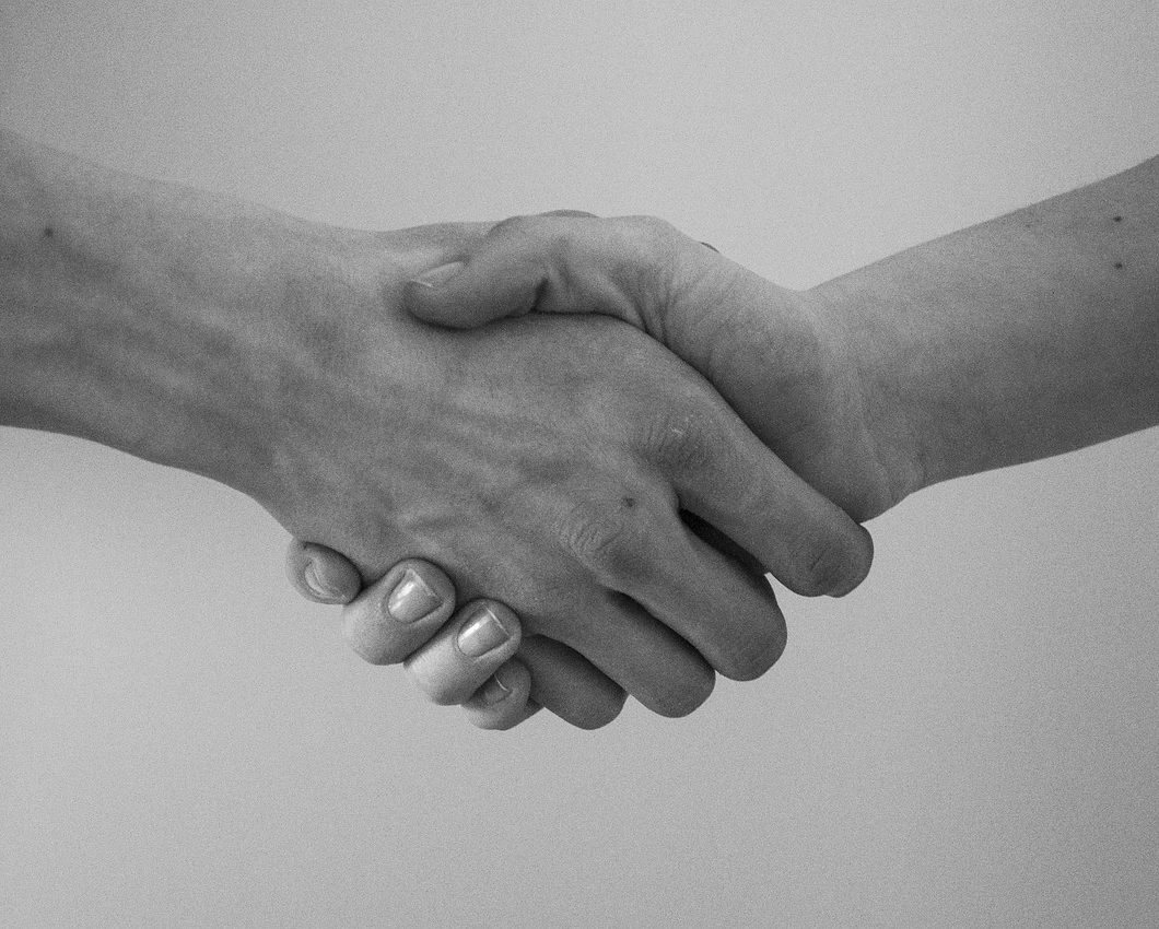 Deux mains se serrent en signe d'accord ou de salutation.